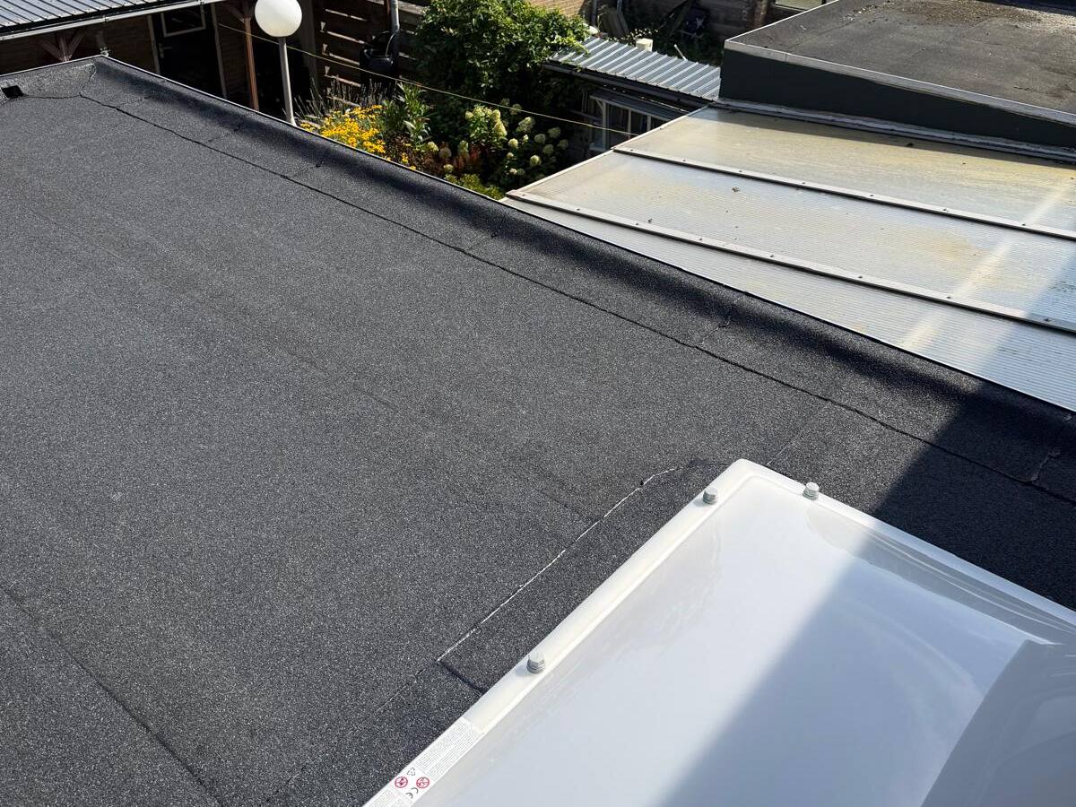 Nieuwe bitumen dakbedekking op een plat dak in een woonwijk